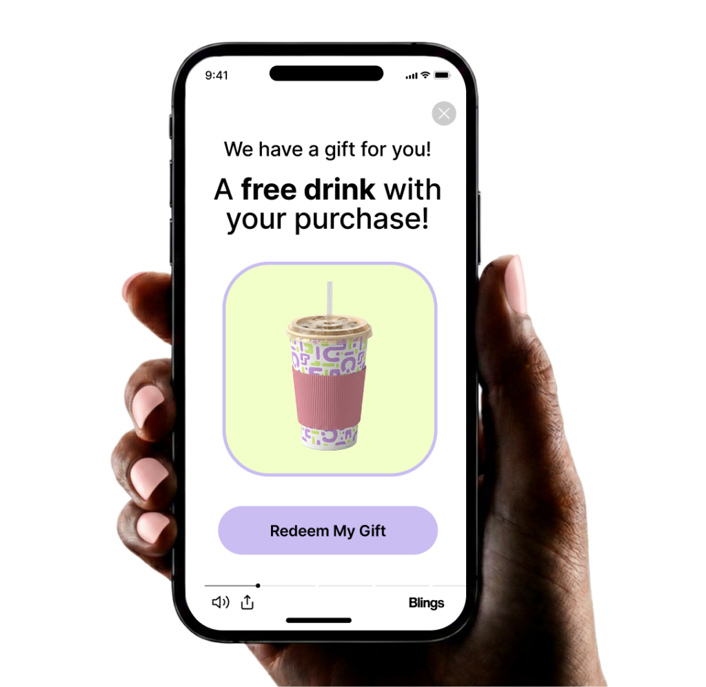 A hand holds a smartphone displaying a personalized video frame that reads We have a gift for you, a free drink with your purchase, above a Redeem My Gift button.