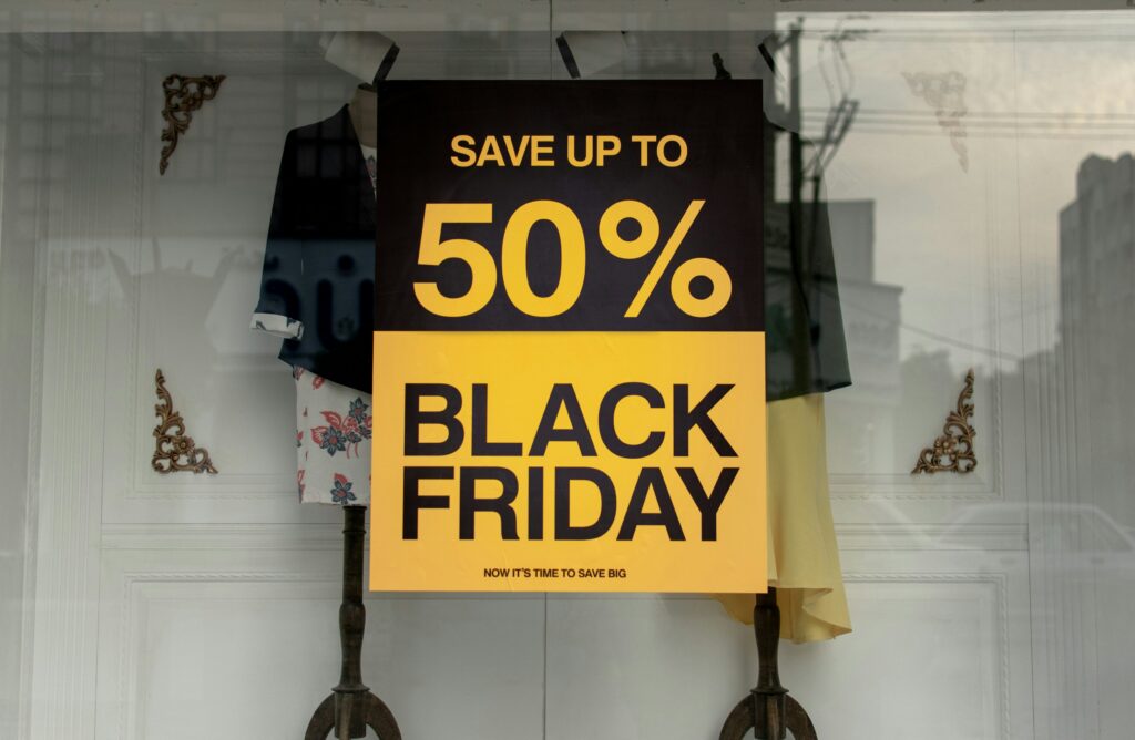 A yellow shop sign reading 50 percent Black Friday displayed in a store window.