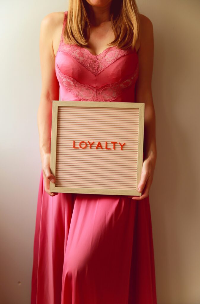 Hands holding a corrugated kraft card with the word loyalty printed in red.